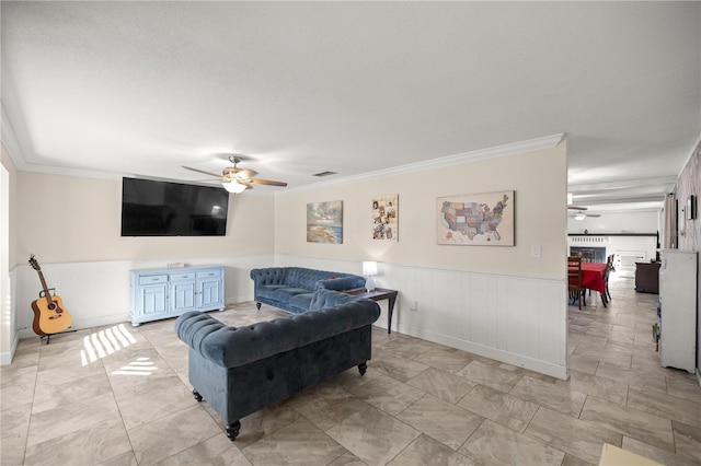 living room featuring ornamental molding, wainscoting, ceiling fan, and visible vents