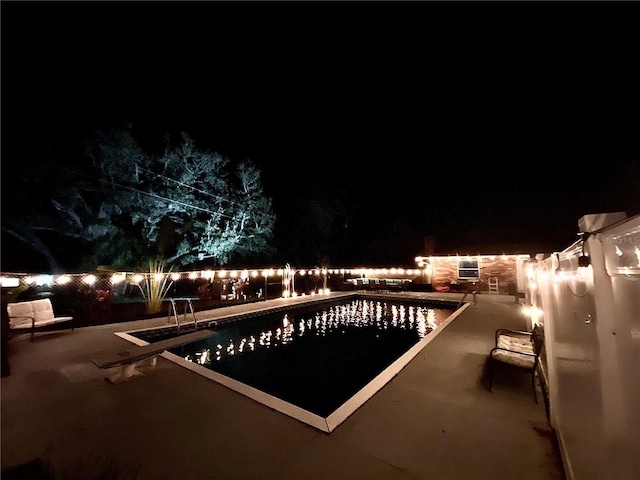 pool at night with a patio area, a fenced backyard, and a fenced in pool