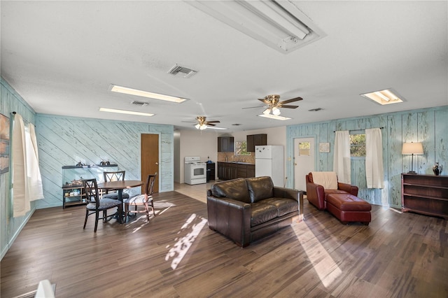 living room with a skylight, plenty of natural light, dark wood finished floors, and visible vents