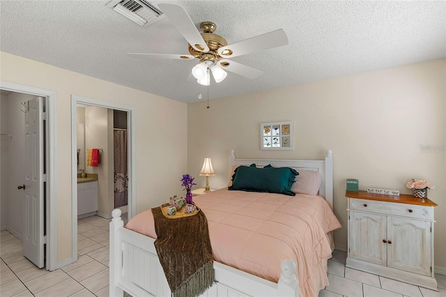 tiled bedroom featuring ensuite bathroom, a textured ceiling, and ceiling fan