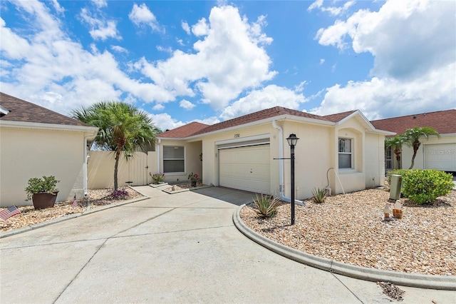 view of front of house with a garage, a gate, driveway, and stucco siding