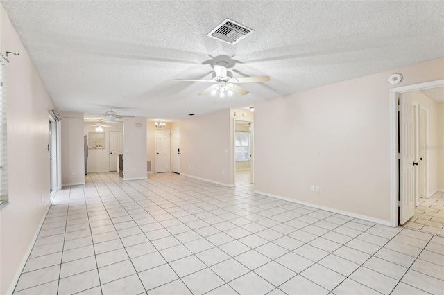 empty room with a textured ceiling, ceiling fan, and light tile patterned flooring