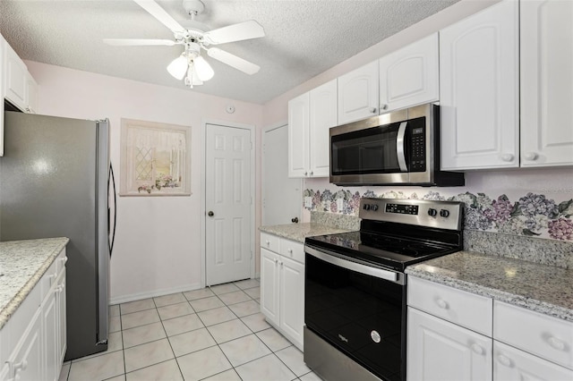 kitchen with stainless steel appliances, a textured ceiling, light tile patterned floors, and white cabinetry