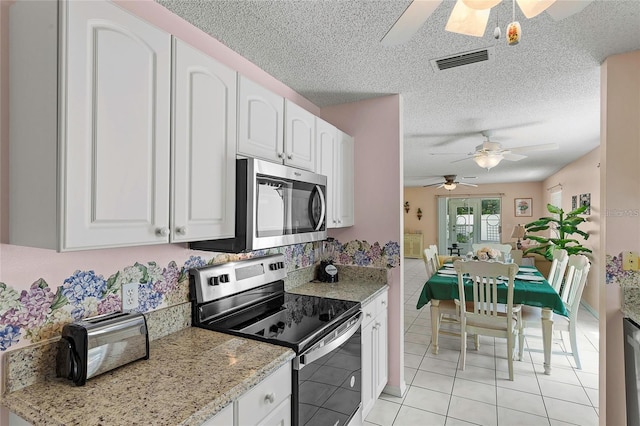 kitchen featuring appliances with stainless steel finishes, light stone countertops, light tile patterned floors, ceiling fan, and white cabinets