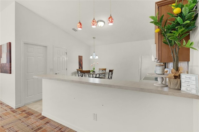 kitchen featuring kitchen peninsula, pendant lighting, and vaulted ceiling