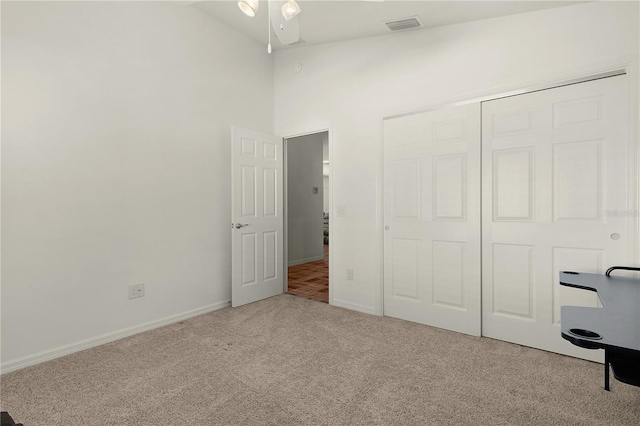 unfurnished bedroom featuring carpet floors, high vaulted ceiling, and a closet