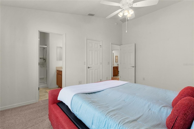 bedroom with ensuite bath, ceiling fan, light colored carpet, and lofted ceiling