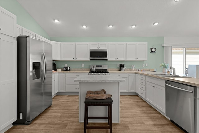 kitchen with appliances with stainless steel finishes, a center island, light hardwood / wood-style floors, and white cabinetry