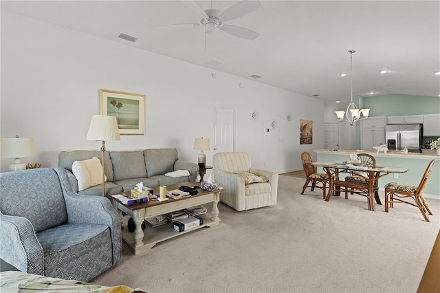 carpeted living room with ceiling fan with notable chandelier and lofted ceiling