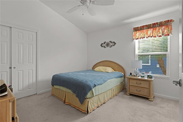 bedroom featuring ceiling fan, vaulted ceiling, light colored carpet, and a closet