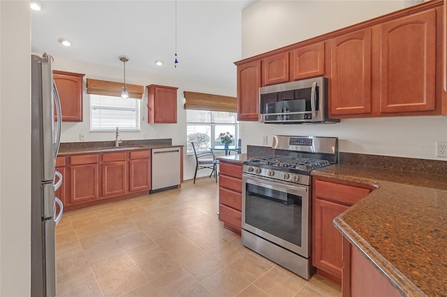 kitchen with dark stone countertops, sink, stainless steel appliances, and decorative light fixtures