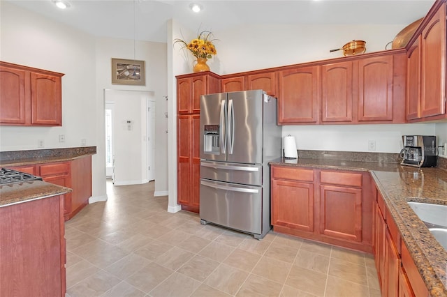 kitchen featuring lofted ceiling, stainless steel refrigerator with ice dispenser, and dark stone counters