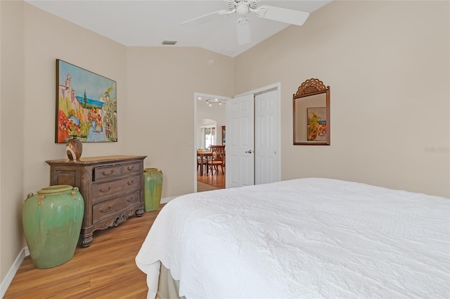 bedroom with ceiling fan, light hardwood / wood-style floors, vaulted ceiling, and a closet