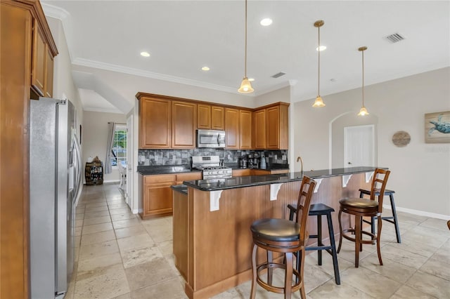 kitchen with hanging light fixtures, tasteful backsplash, a kitchen breakfast bar, dark stone counters, and appliances with stainless steel finishes