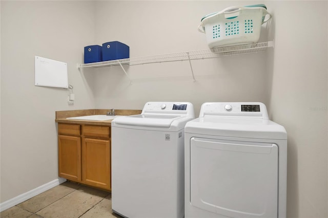 clothes washing area with washing machine and dryer, sink, and cabinets