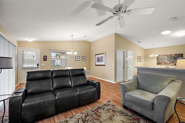 living room featuring lofted ceiling, ceiling fan with notable chandelier, a textured ceiling, and hardwood / wood-style floors