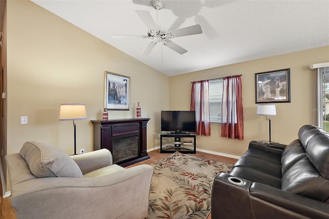 living room with ceiling fan, hardwood / wood-style floors, lofted ceiling, and a textured ceiling