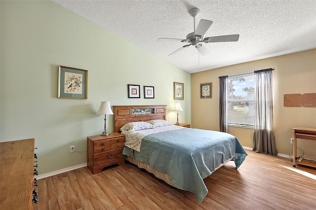 bedroom with a textured ceiling, ceiling fan, vaulted ceiling, and light wood-type flooring