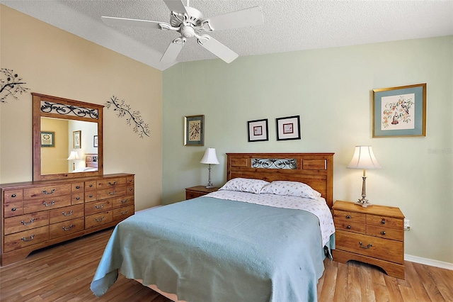 bedroom with ceiling fan, vaulted ceiling, a textured ceiling, and wood-type flooring