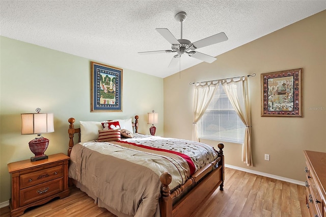 bedroom featuring lofted ceiling, light wood-type flooring, ceiling fan, and a textured ceiling