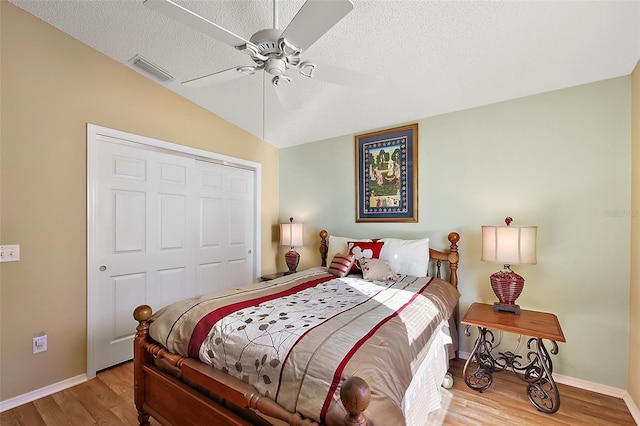 bedroom with a closet, light wood-type flooring, ceiling fan, a textured ceiling, and lofted ceiling