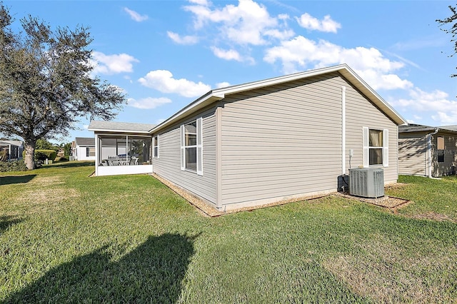 view of side of home featuring central AC, a sunroom, and a lawn