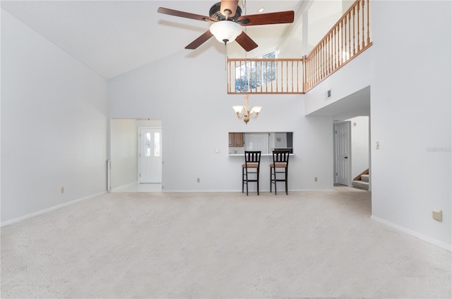 unfurnished living room featuring light carpet, high vaulted ceiling, and ceiling fan with notable chandelier