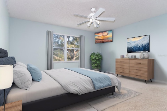 bedroom with ceiling fan, light carpet, and a textured ceiling