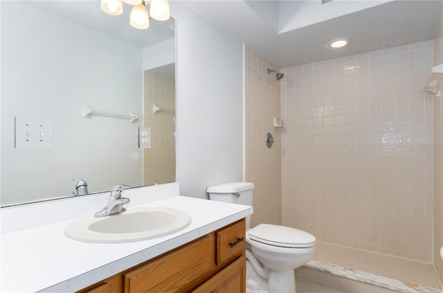 bathroom with tiled shower, vanity, and toilet