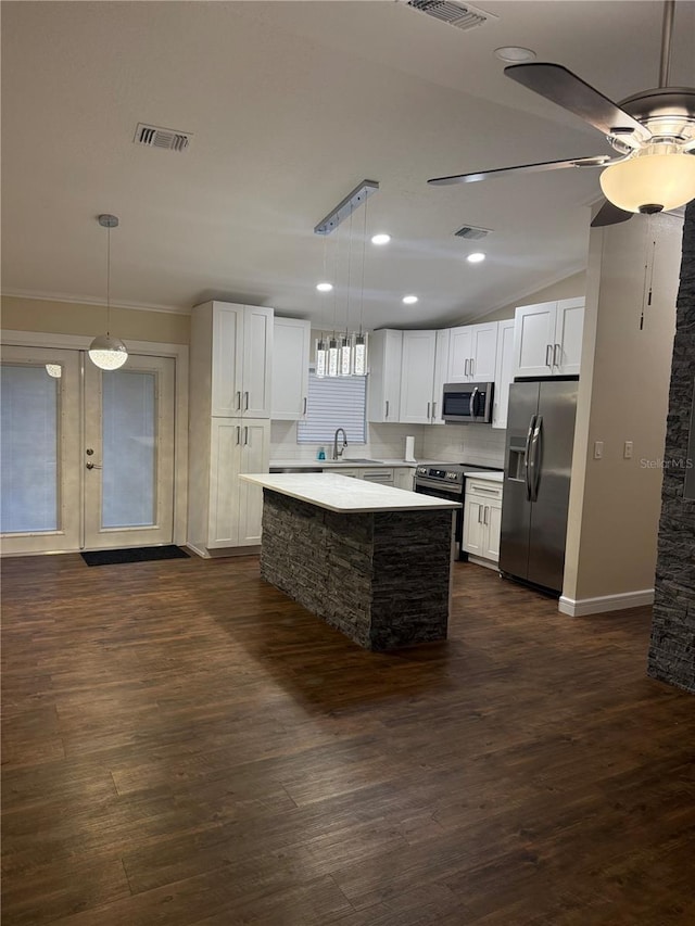 kitchen with white cabinetry, dark wood-type flooring, hanging light fixtures, stainless steel appliances, and a kitchen island