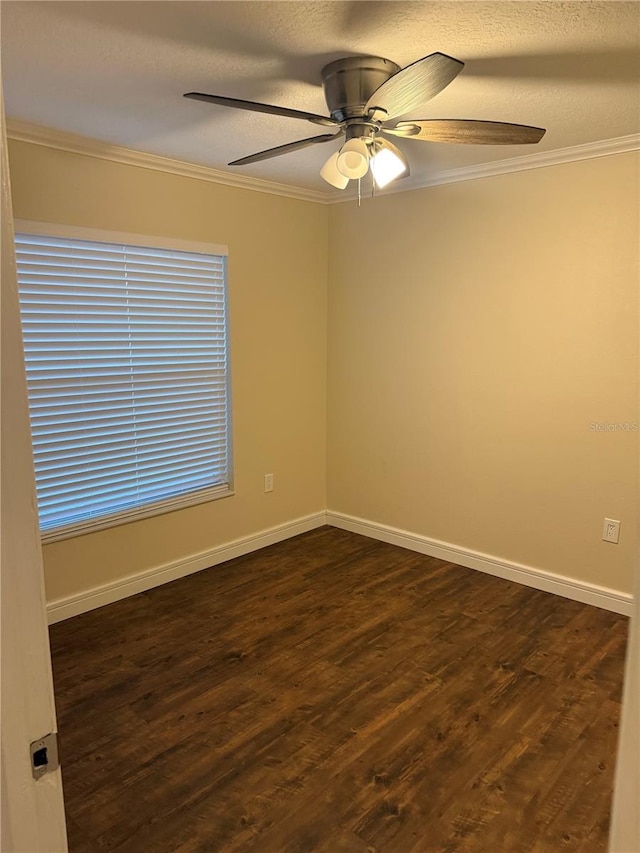 spare room featuring dark wood-type flooring, a ceiling fan, baseboards, and ornamental molding