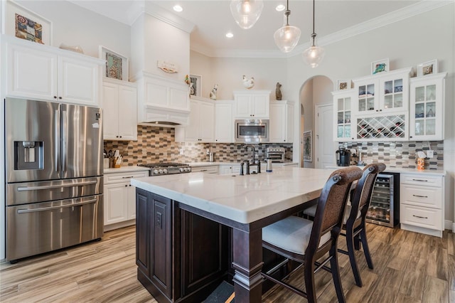 kitchen featuring appliances with stainless steel finishes, light stone counters, pendant lighting, a center island with sink, and white cabinets