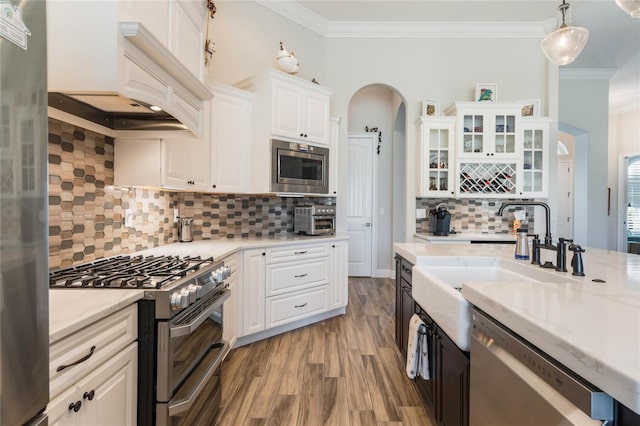 kitchen with stainless steel appliances, backsplash, decorative light fixtures, white cabinets, and custom range hood