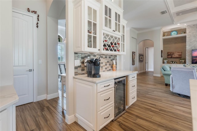 kitchen featuring white cabinetry, beverage cooler, crown molding, hardwood / wood-style floors, and decorative backsplash