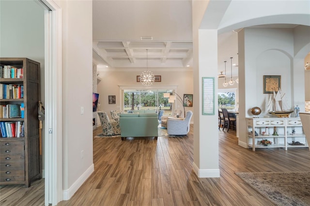 hall featuring coffered ceiling, beamed ceiling, crown molding, a chandelier, and hardwood / wood-style flooring