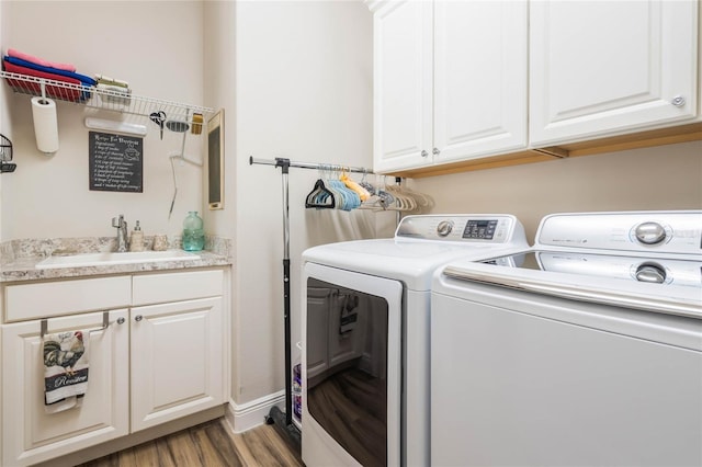 washroom with cabinets, light hardwood / wood-style floors, washing machine and dryer, and sink