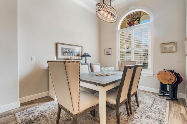 dining space with crown molding, wood-type flooring, and an inviting chandelier