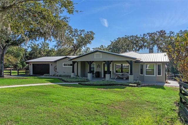 single story home with metal roof, an attached garage, fence, stucco siding, and a front lawn