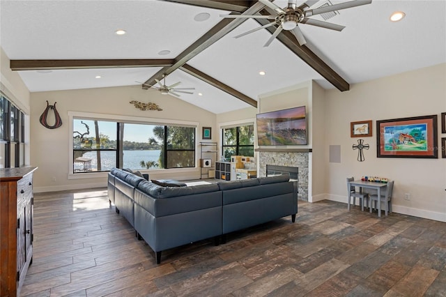 living area with dark wood finished floors, lofted ceiling with beams, a ceiling fan, a stone fireplace, and baseboards