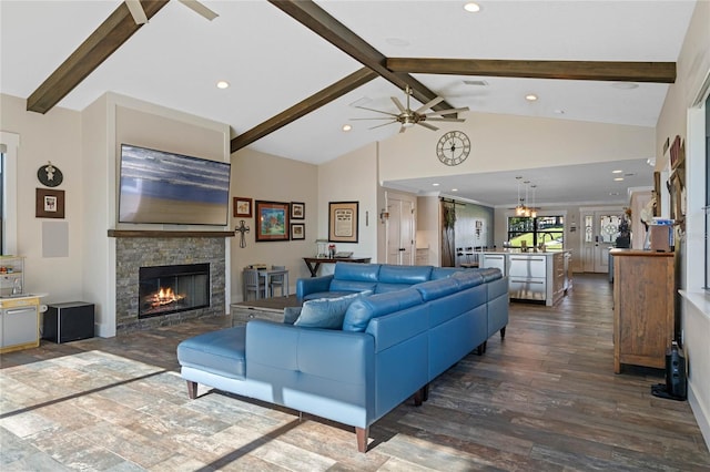 living area featuring dark wood finished floors, recessed lighting, a stone fireplace, beamed ceiling, and ceiling fan with notable chandelier