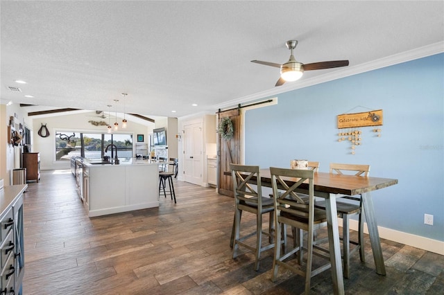 dining room with a barn door, visible vents, dark wood-type flooring, and ornamental molding