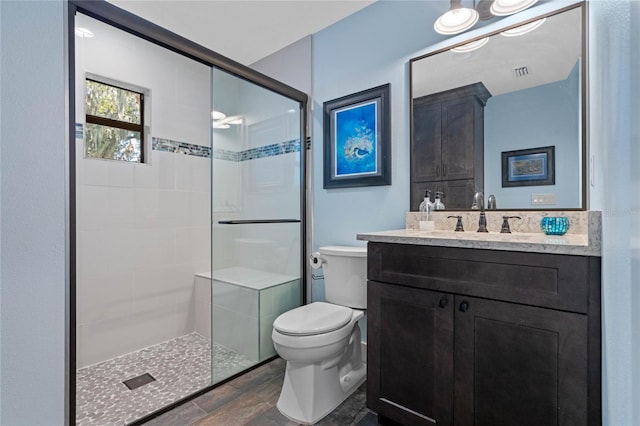 bathroom featuring toilet, tiled shower, and vanity