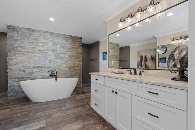 bathroom with a soaking tub, ornamental molding, wood finished floors, a textured ceiling, and vanity