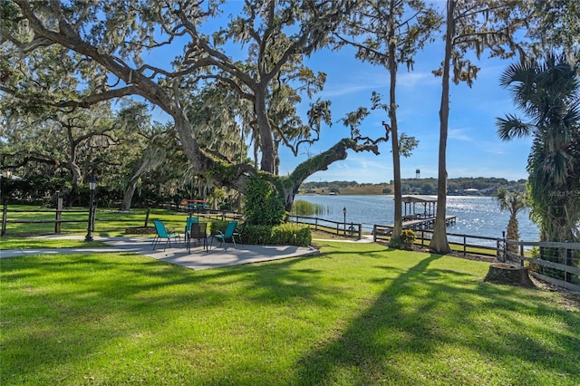 view of yard with a boat dock, a water view, and fence