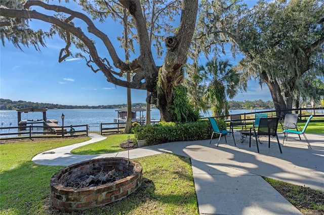 exterior space with an outdoor fire pit, a water view, a yard, and a dock