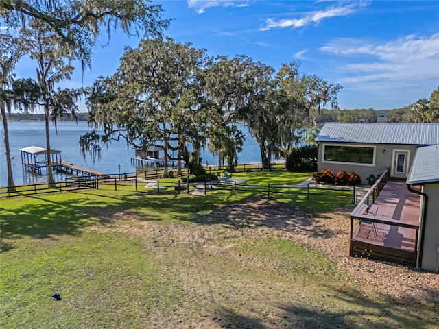 view of yard with a boat dock, a water view, and fence