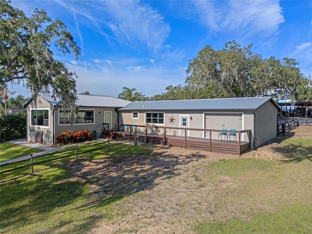 rear view of property with fence, metal roof, and a yard