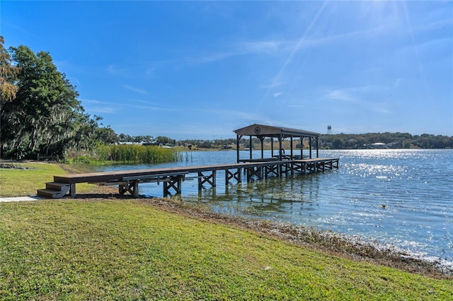 dock area with a lawn and a water view