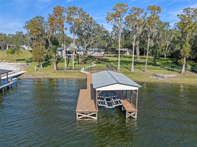 view of dock with a water view and a lawn