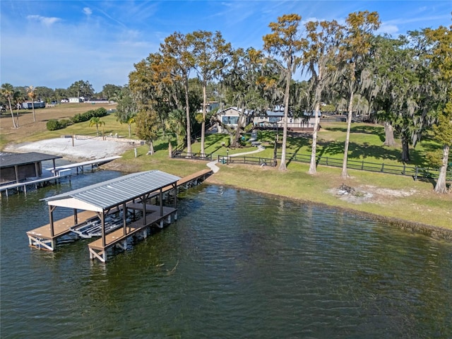 view of dock with boat lift, a lawn, a water view, and fence